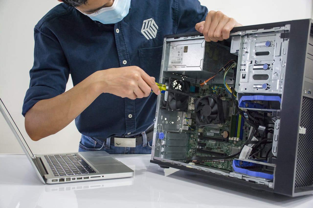services-05 A technician repairs a desktop computer in an indoor setting, illustrating tech maintenance.