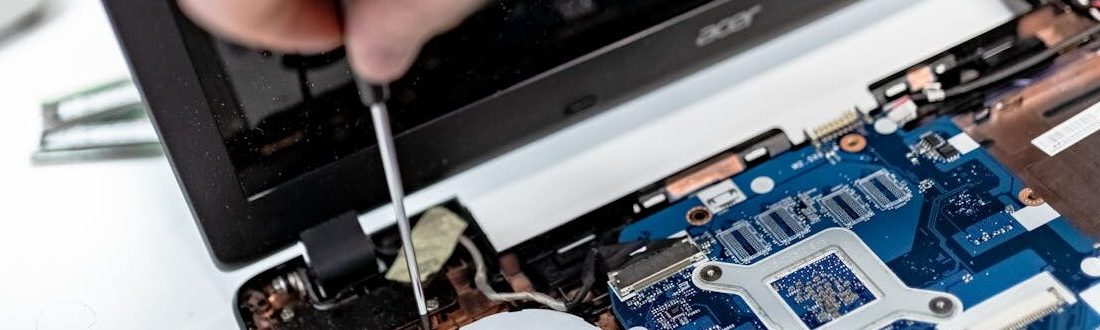 Technician repairing a laptop motherboard, focusing on electronic components.